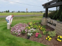 Volunteer Kathy Mahnerd tending entrance flowers she planted.
